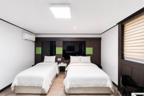 a room with two beds and a table in it at Osan J Hotel in Osan
