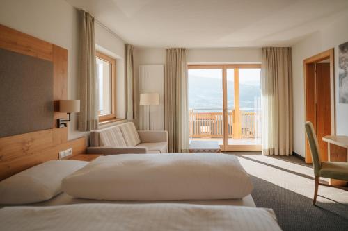 ein Hotelzimmer mit zwei Betten und Balkon in der Unterkunft Panorama Hotel Flora in Villanders