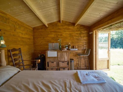a bedroom with a bed in a wooden cabin at Simple Basketmakers Hut Cabin for Two in Chiddingstone