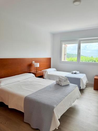 a bedroom with two beds and a window at Pensión San Antón in Sanxenxo