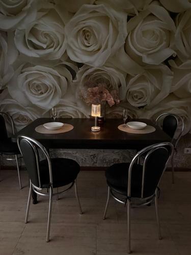 a table with chairs and a wall with roses at Затишні апартаменти Східна Перлина in Vinnytsya