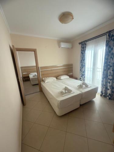 a bedroom with a large bed and a mirror at Dafni Seaside Hotel in Leptokarya