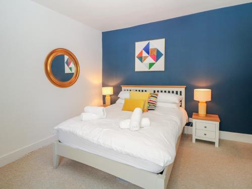 a bedroom with a white bed with a blue wall at Cosy Cottage in Buxton