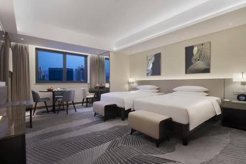 a hotel room with two beds and a table and chairs at Hyatt Regency Metropolitan Chongqing in Chongqing