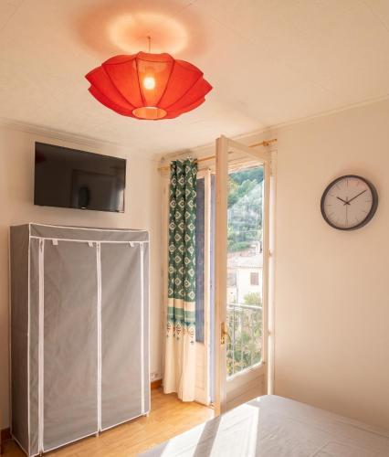 a room with a sliding glass door and a clock at Studio confortable, Rennes les bains, 17 m² + Balcon in Rennes-les-Bains