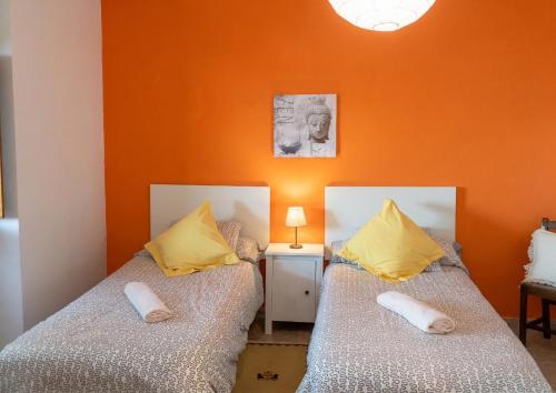 two beds in a room with an orange wall at Charming house in Teror with garden in Teror