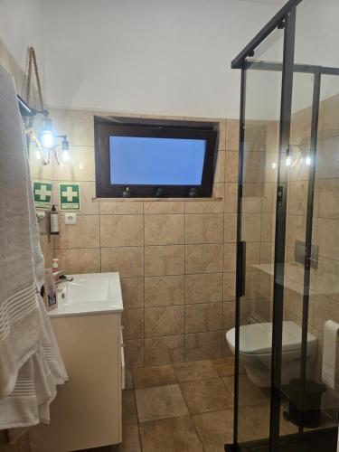 a bathroom with a tv on the wall and a sink at Casa Saudade Beach House in Zambujeira do Mar