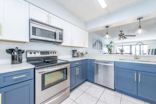 a kitchen with blue cabinets and a stove top oven at Sandcastles - Cocoa Beach Oceanfront Condos with Heated Pool Tennis in Cocoa Beach