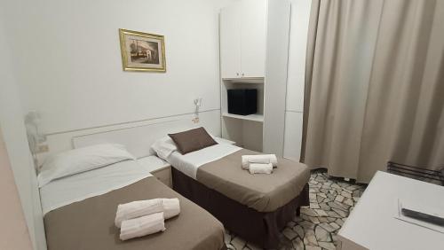 a hotel room with two beds and a television at Hotel Cilene in Viareggio