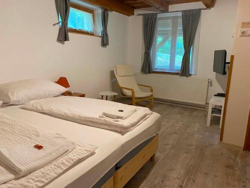 a room with two beds and a chair in it at Flóra Apartmanok in Kehidakustány
