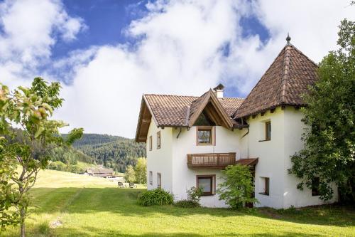 a white house with a brown roof on a green field at Apartments Schießstand in Avelengo
