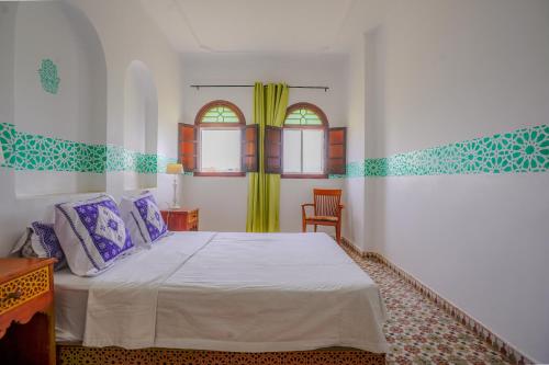 a bedroom with a bed and two windows at Riad Salt River in Martil