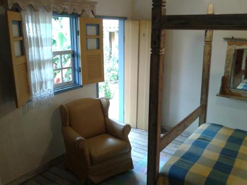 a bedroom with a chair and a bed and a window at Arraial Velho Pousada Tematica in Tiradentes
