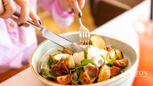 a person eating a bowl of salad with a fork and knife at Hotel Aro Palace in Braşov