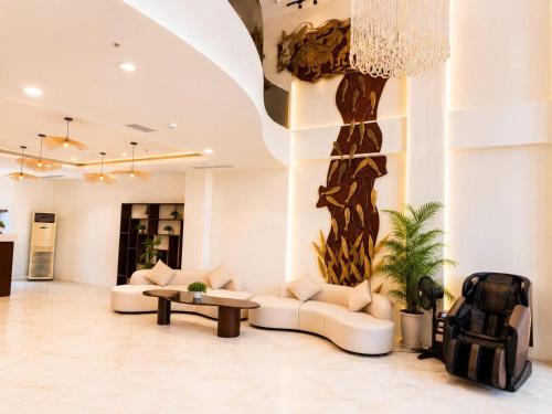 a living room with couches and a tree on the wall at LAVISH OCEAN INN Đà Nẵng in Danang