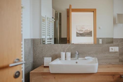 ein Badezimmer mit einem weißen Waschbecken und einem Spiegel in der Unterkunft Panorama Hotel Flora in Villanders