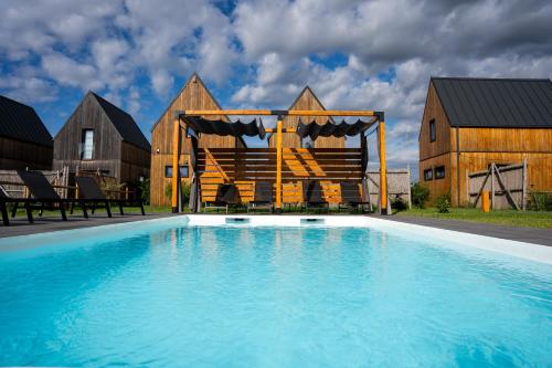 a swimming pool with a gazebo and a house at Letnisko Rusinowo in Jarosławiec