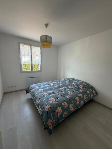 a bedroom with a bed with a floral blanket at La Parenthèse Immo in Amilly