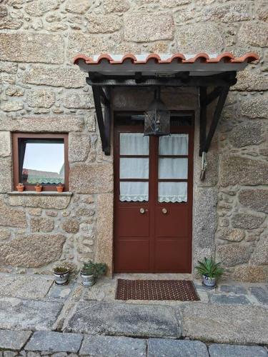 a brick building with a red door and a window at Casa do Muro Alto in Alvelos