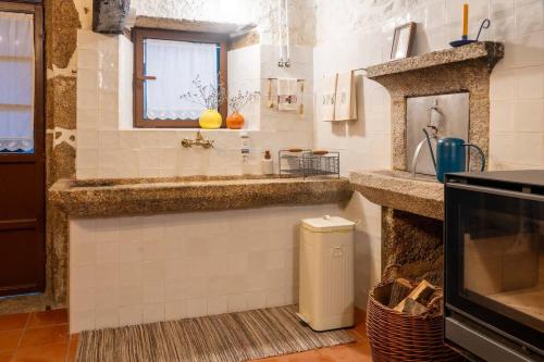a kitchen with a counter with a sink and a window at Casa do Muro Alto in Alvelos