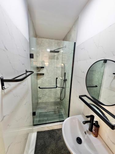 a bathroom with a shower and a sink and a mirror at Luxury 2BR Oasis in Lekki