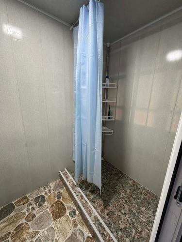 a shower with a blue curtain in a room at Guest House Nazo in Omalo