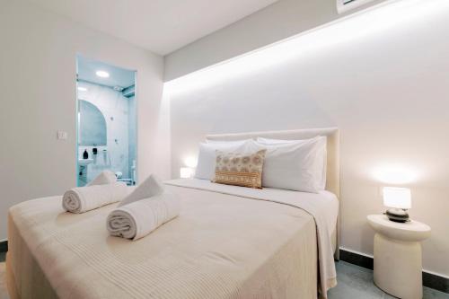 a white bedroom with a bed with towels on it at A&B Rooms Rodos Center in Rhodes Town