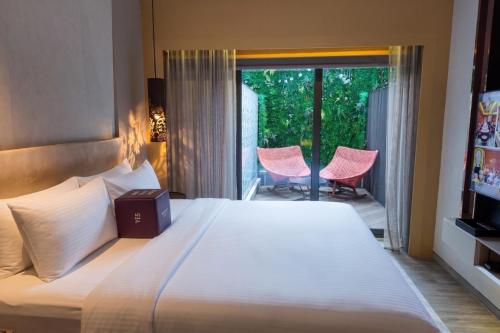a bedroom with a bed and a balcony with pink chairs at Naumi Hotel Singapore in Singapore