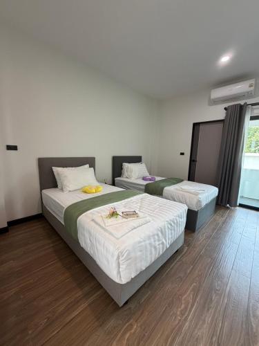 two beds in a room with wooden floors at AlinApartment in Ban Sa Kruat