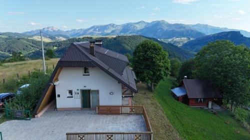 a small white house with mountains in the background at Utopia Mountain resort Bjelasnica in Bjelašnica