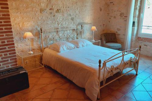 a bedroom with a bed and two lamps and a chair at Clos de la Dîme in Lombers