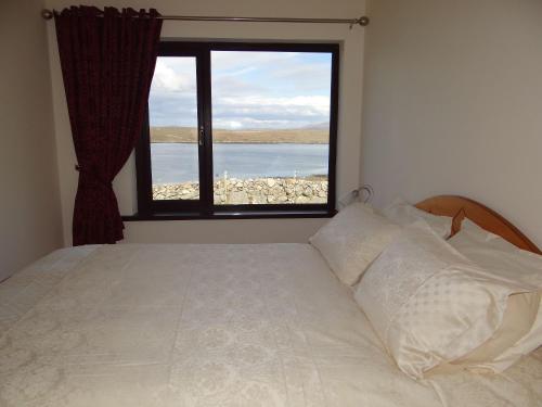 a bedroom with a bed and a large window at Cill Cottage in Roundstone