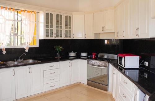 a kitchen with white cabinets and black counter tops at Elegant Villa in Nagua with Private Pool and Jacuzzi in Nagua