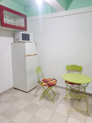 a kitchen with a table and chairs and a refrigerator at Studio charmant à Rivière Salée - 22 m² + Parking in Rivière-Salée