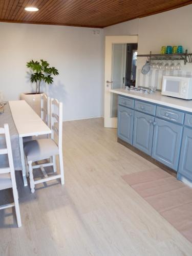 a kitchen with blue cabinets and a table and chairs at Charming House in Requião with Shared Pool in Requião