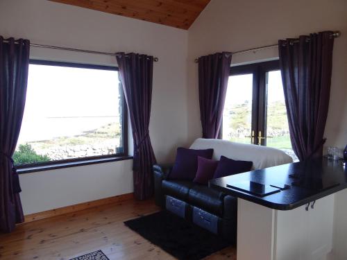 a living room with a couch and large windows at Cill Cottage in Roundstone