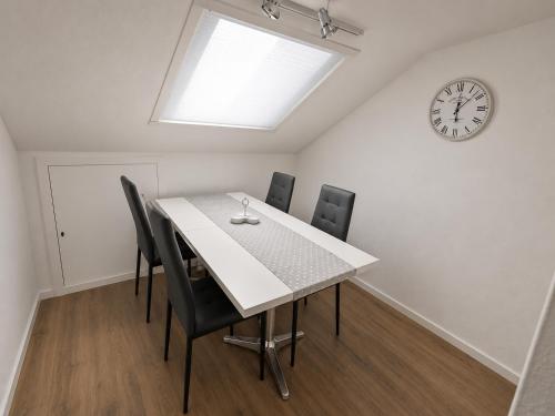 a dining room with a table and chairs and a clock at M&M Apartments in Augustdorf