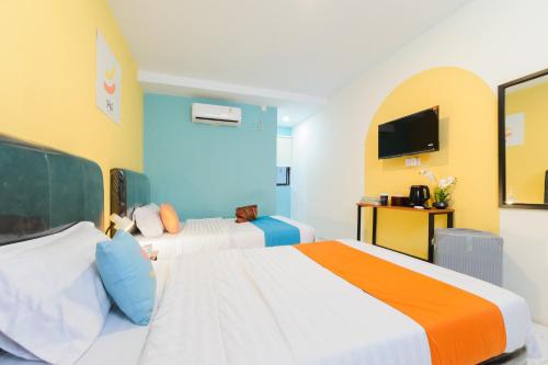 a hotel room with two beds and a tv at Sans Hotel Sedana Batam in Nagoya