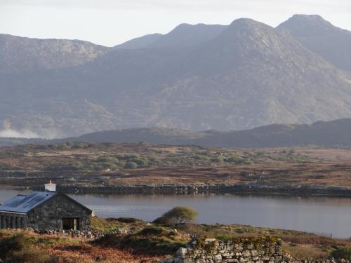 an old house on the side of a lake with mountains at Cill Cottage in Roundstone