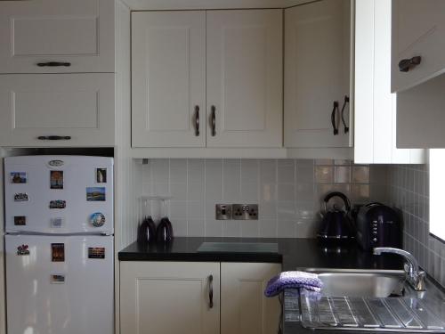 a kitchen with white cabinets and a white refrigerator at Cill Cottage in Roundstone