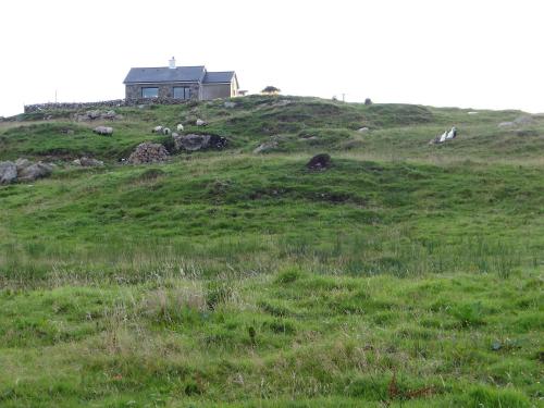 a house on top of a grassy hill at Cill Cottage in Roundstone