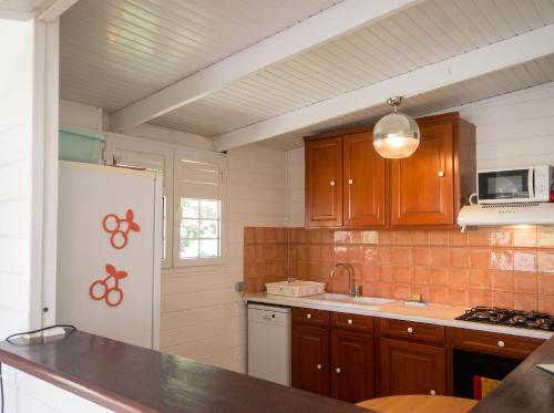 a kitchen with wooden cabinets and a white refrigerator at Appartement spacieux au Vauclin avec piscine privée in Le Vauclin