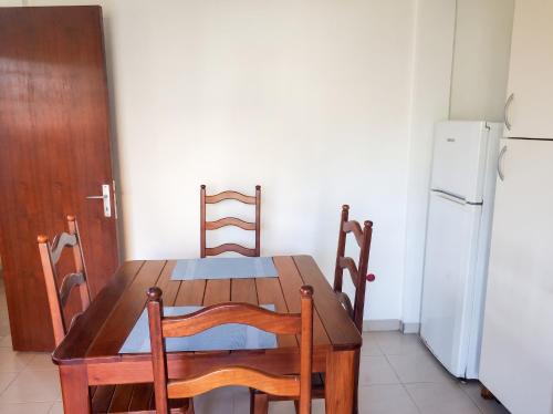 a wooden table and chairs in a kitchen with a refrigerator at Appartement charmant au Lamentin avec terrasse et jardin, 46 m² in Le Lamentin