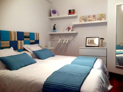 a bedroom with two beds with blue pillows at Apartamento Playa Poniente in Gijón