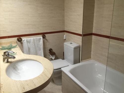 uma casa de banho com um lavatório, um WC e uma banheira em Apartamento Playa Poniente em Gijón
