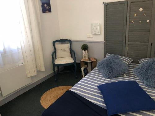 a bedroom with a blue and white bed and a chair at Chambre la paix verte in Payrac