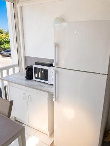 a kitchen with a white refrigerator and a microwave at Studio romantique à Saint-François - 25 m² avec piscine in Saint-François