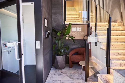 a hallway with a staircase with a chair and a plant at Medichë Rooms General Ricardos in Madrid