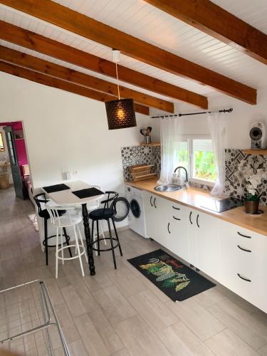 a kitchen with white cabinets and a table with chairs at Studio cosy à Capesterre-Belle-Eau avec terrasse in Capesterre-Belle-Eau