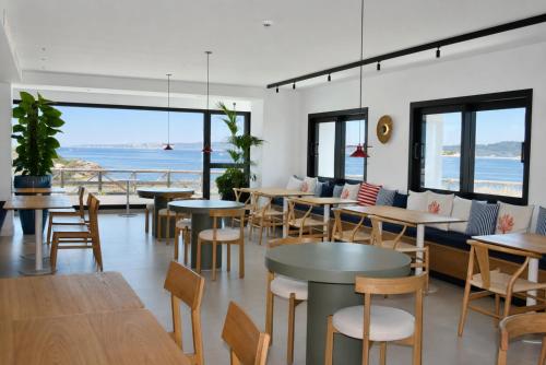 ein Restaurant mit Tischen und Stühlen und Meerblick in der Unterkunft Hotel Delfin Azul in A Lanzada